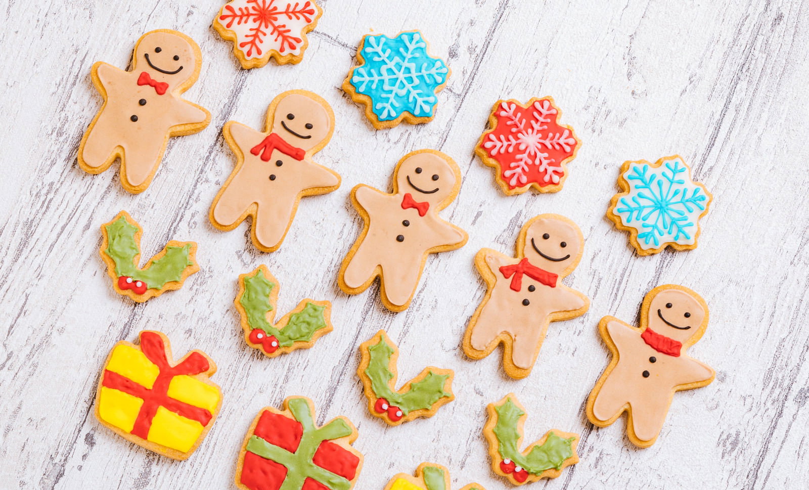 白い木目の背景にクリスマス用アイシングクッキーが並ぶ
