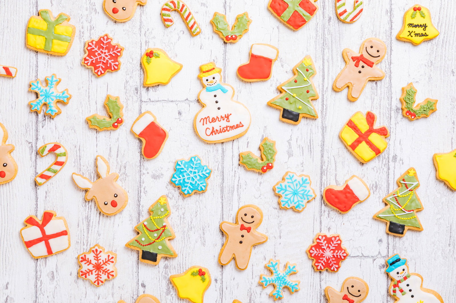 白い木製の背景に並べられた可愛いキャラクターのクリスマスアイシングクッキー