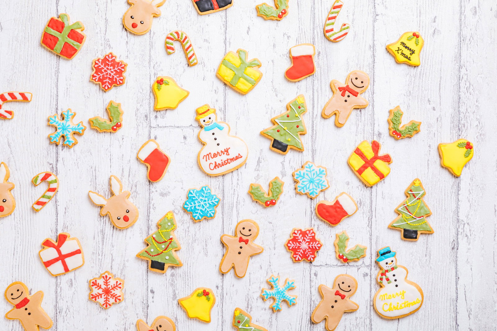 白い木目の板に散りばめられたクリスマスアイシングクッキー