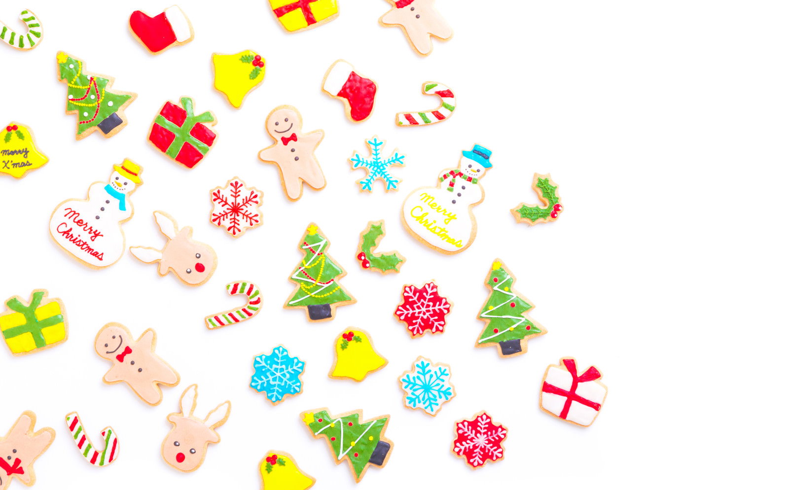 白い背景に散らばったクリスマステーマのアイシングクッキー