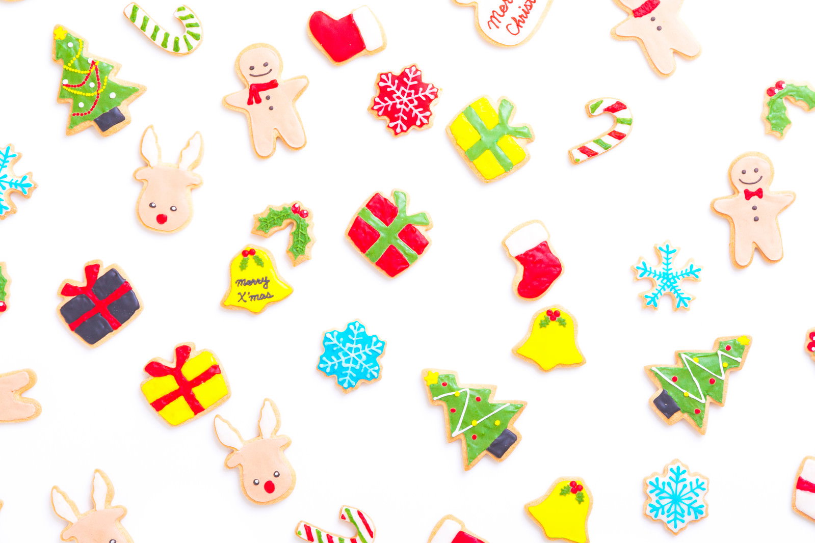 白い背景に散りばめられたカラフルなクリスマスアイシングクッキー