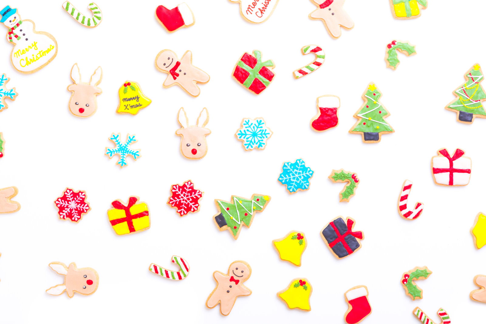 白い背景に散りばめられたカラフルなクリスマス用アイシングクッキー