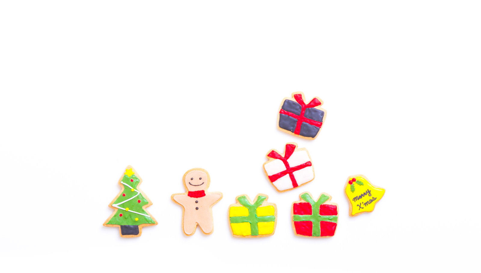 白い背景にクリスマスツリーやジンジャーマンなどのアイシングクッキーとプレゼントが並んでいる