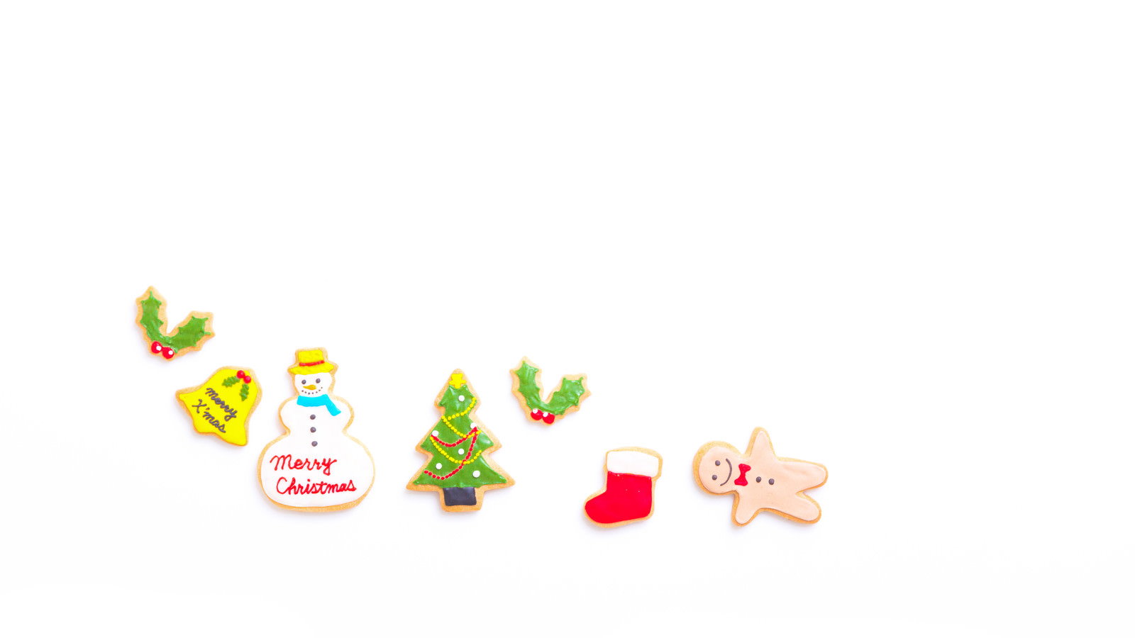 白い背景にクリスマス柄のアイシングクッキーと赤い靴下が並んでいる