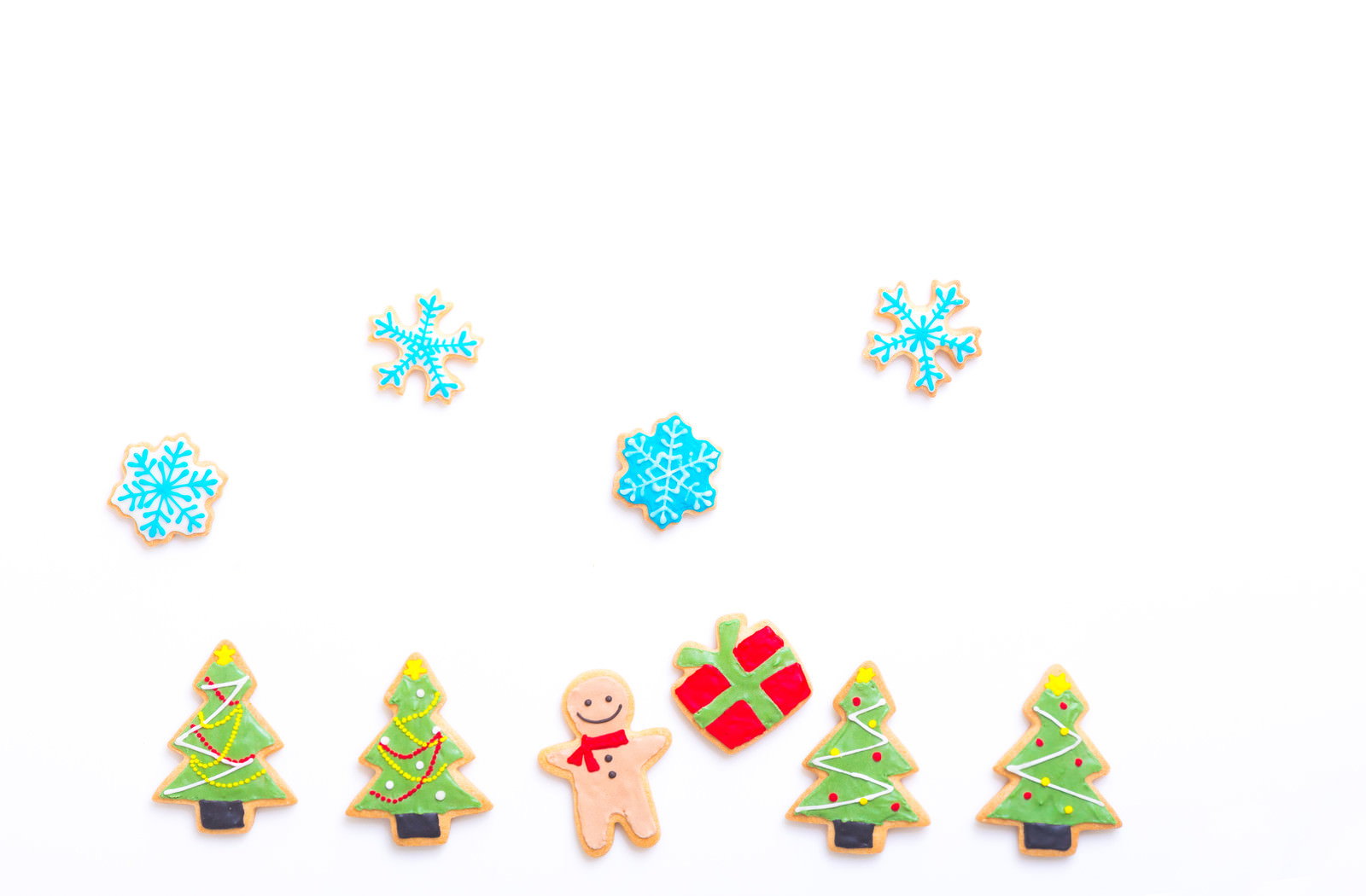 白い背景に並んだクリスマスツリーとプレゼントのアイシングクッキー