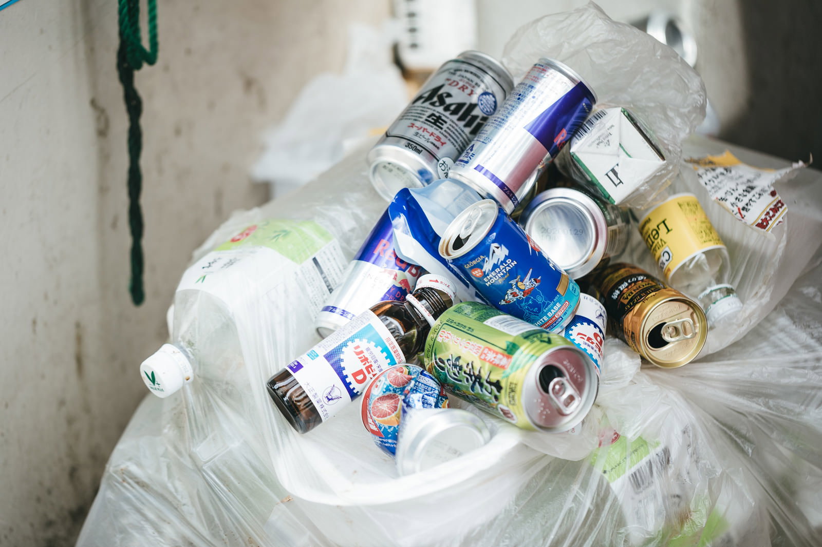 Discarded empty cans and bottles scattered around a white trash bag