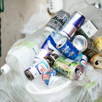 ゴミ袋の周りに捨てられていく空き缶とポイ捨てのゴミ山の写真