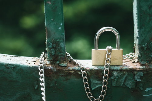 緑色の柵に繋がるチェーン付き南京錠の防犯セキュリティ対策