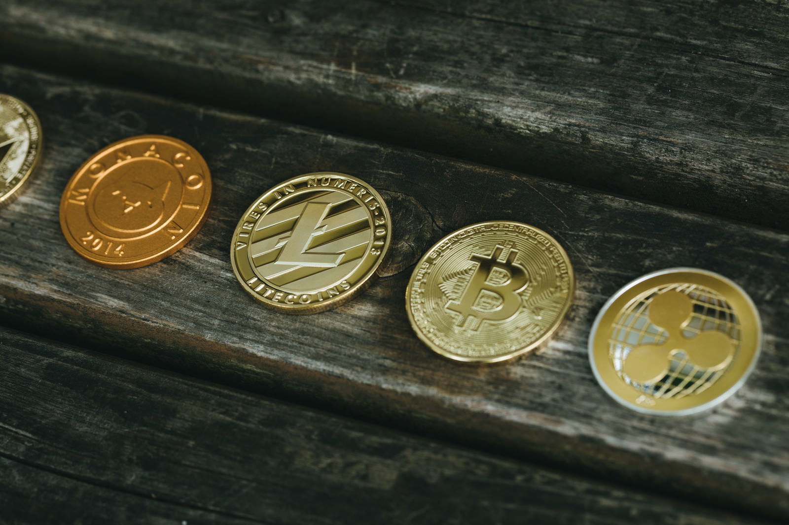 木製テーブルの上に一列に並べられた金色と銀色の仮想通貨コイン