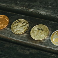 木製テーブルに並べられた仮想通貨コインたちの写真