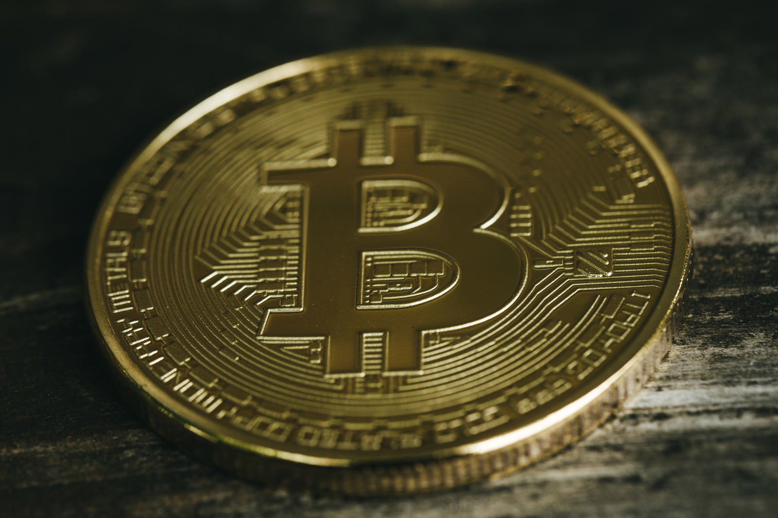 木製テーブルの上に置かれた金色のビットコインコイン