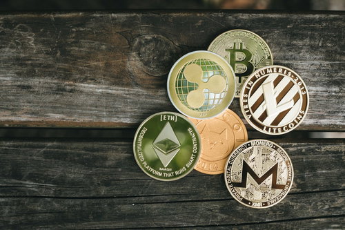 複数の暗号資産が集めた仮想通貨コイン、木製テーブルに並ぶ
