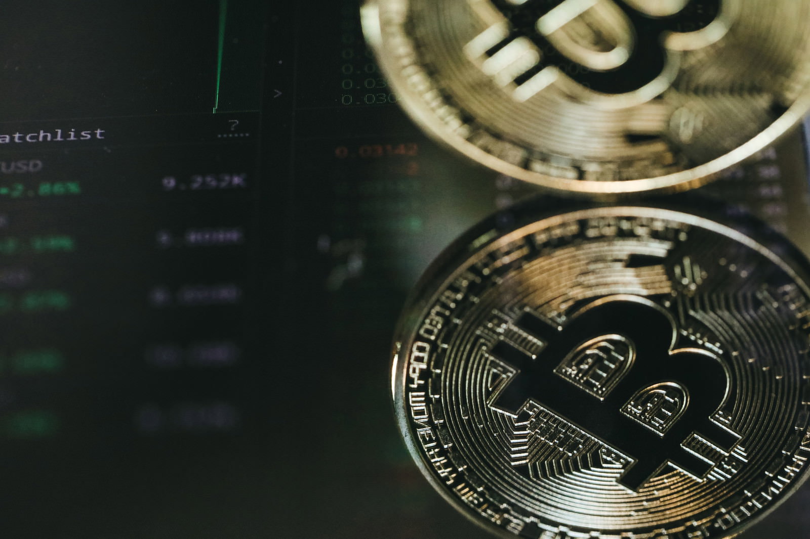 金色のビットコインが複数枚配置されレート一覧が背景に映る