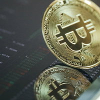 取引画面に映りこむ金色のビットコイン（仮想通貨）の写真