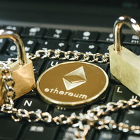 キーボード上に置かれた金色のイーサリアムコインと南京錠の写真