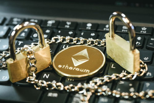 キーボード上に置かれた金色のイーサリアムコインと南京錠