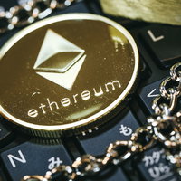 キーボード上に置いた金色のチェーンとイーサリアム（ETH）コインの写真