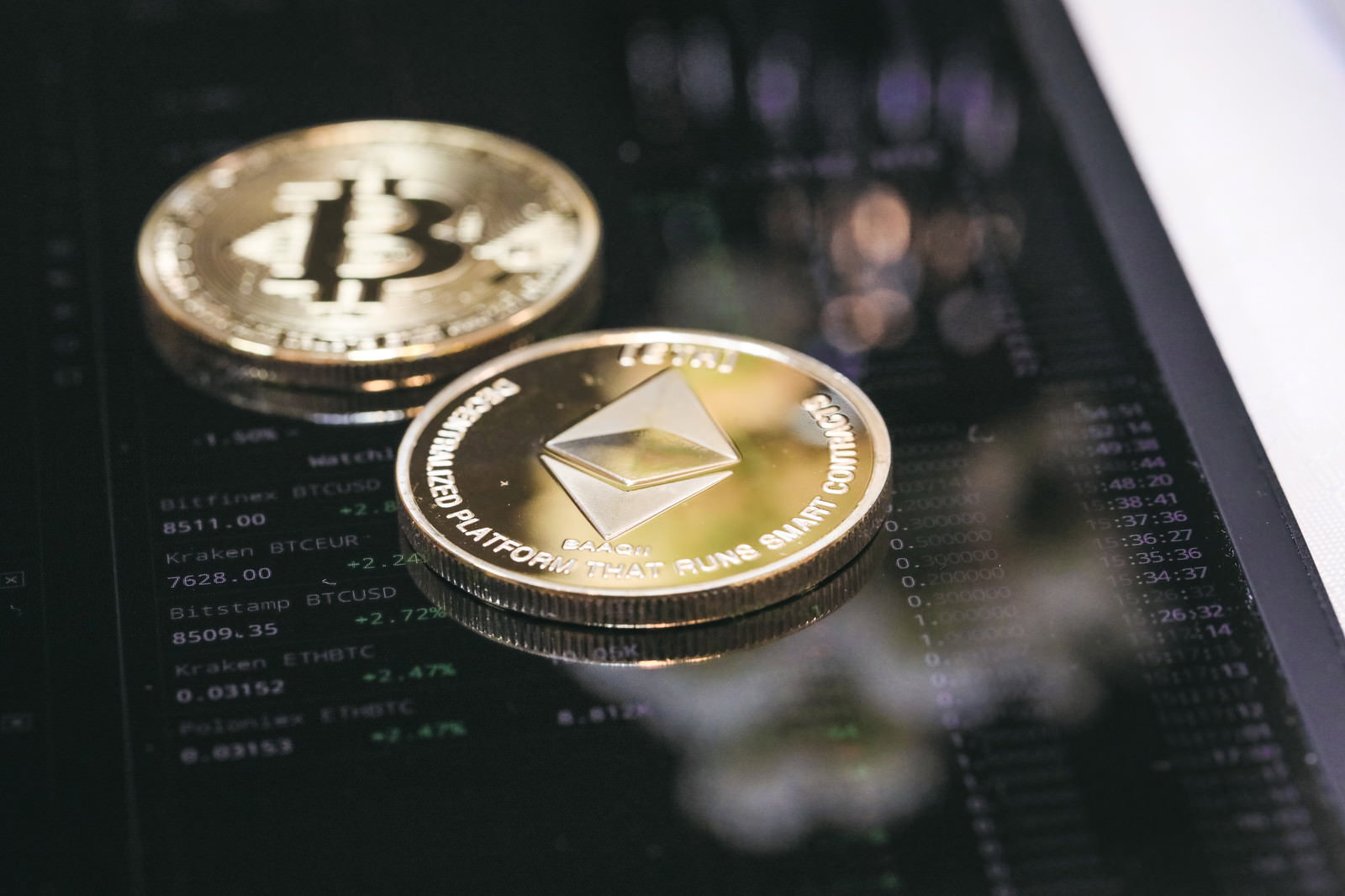 スマートフォンの画面上に置かれたビットコインとイーサリアムのコイン