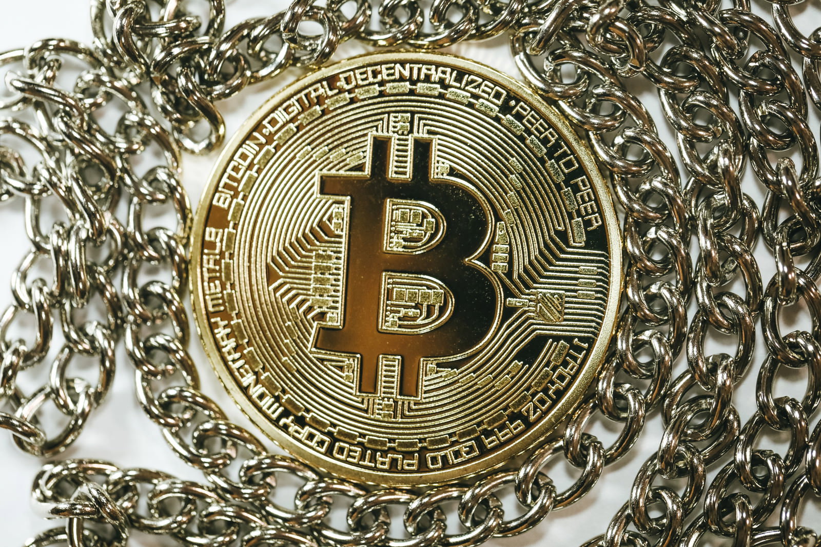 金色のビットコインコインが銀色のチェーンの中心に配置されている