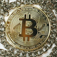 銀色のチェーンの中心に配置された金色のビットコインの写真