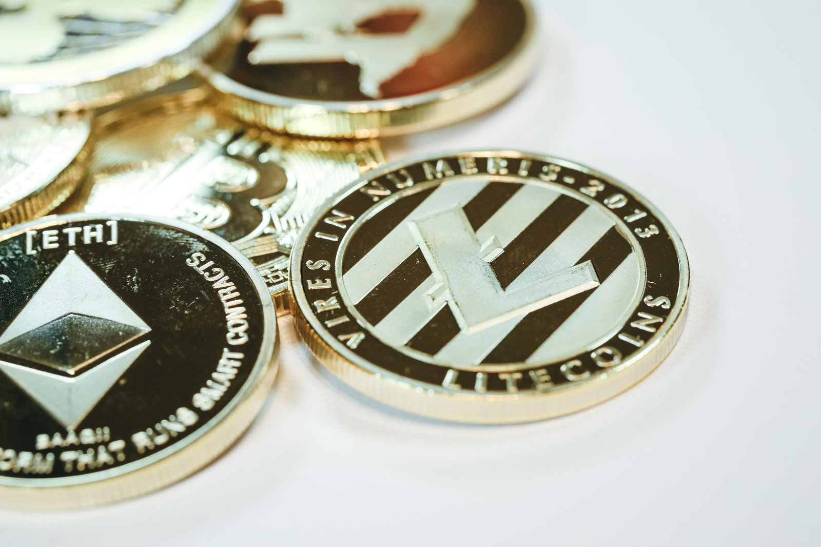 テーブルの上に無造作に置かれたイーサリアムやライトコインなどの仮想通貨コイン