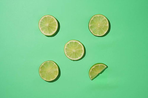 緑の背景に配置されたカットライムの輪切り