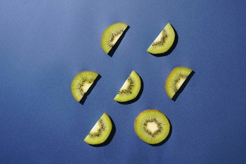 青い背景に並ぶ輪切りとカットされたキウイフルーツ