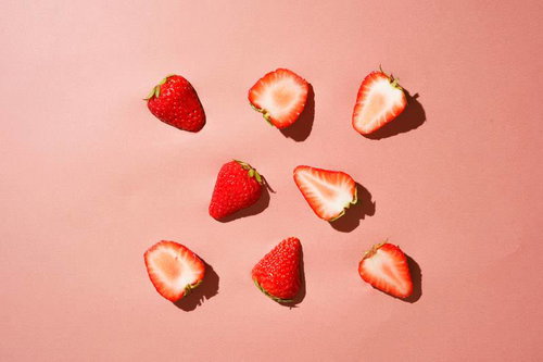 ラブリーストロベリーのカットフルーツ、ピンク背景に並べたいちご