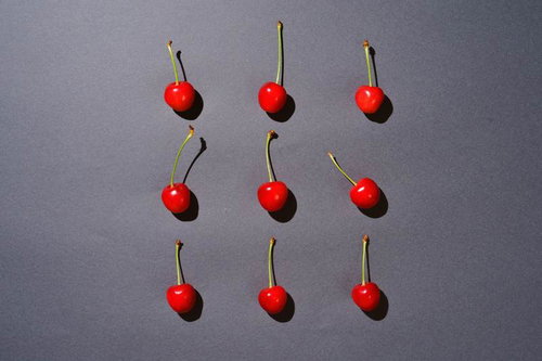 グレーの背景に規則正しく並べられた串刺しチェリー9個