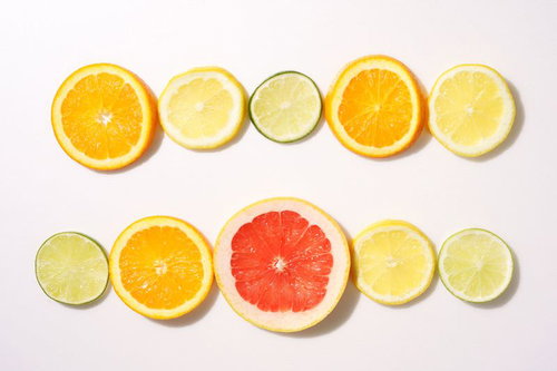 白い背景に並ぶ輪切りの柑橘系果物、オレンジ、レモン、ライム、グレープフルーツ