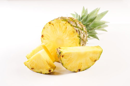 白い背景に並ぶ輪切りのパイナップルと丸ごと一個