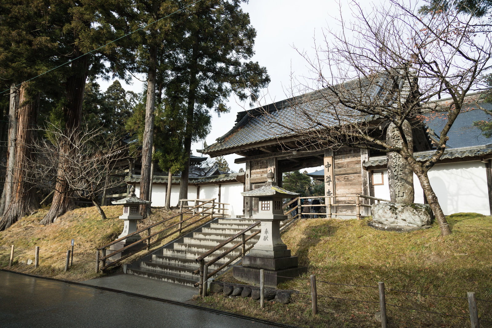 石段の上に建つ中尊寺本坊表門と周囲の杉の木々