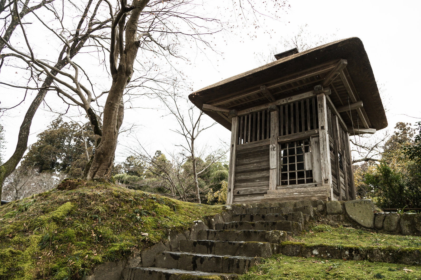 石段の上に建つ木造の梵鐘堂と吊り下げられた梵鐘