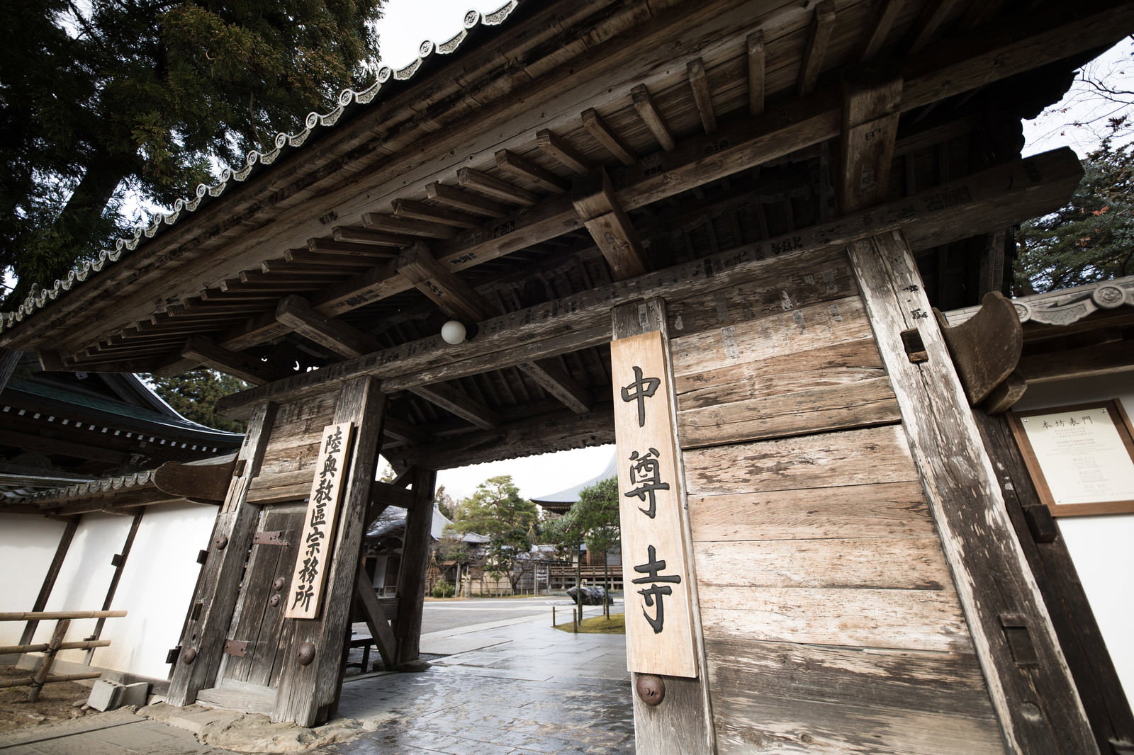 木造建築の重厚な門の向こうに本堂の屋根が見える中尊寺本堂の門