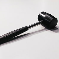 白い背景に横たわる黒いハンドルのハンマーの写真