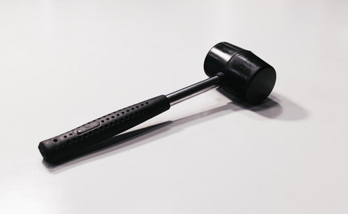 白い背景に横たわる黒いハンドルのハンマー