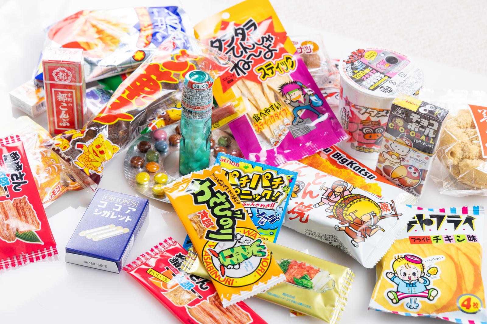 コンビニで売られているカラフルなパッケージの日本のお菓子と飲料が白背景に並んでいる