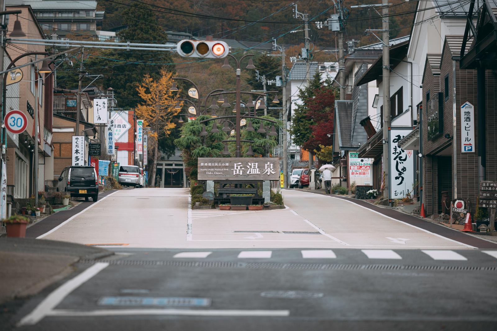 岳温泉のヒマラヤ大通りで三色信号機が設置された道路と両側の看板、奥に秋の紅葉が見える温泉街