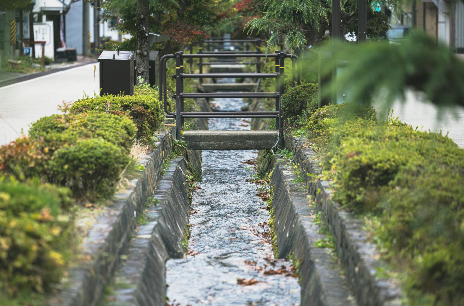 岳温泉のヒマラヤ大通りで石垣に挟まれた小川が流れ、黒い橋が架かっている