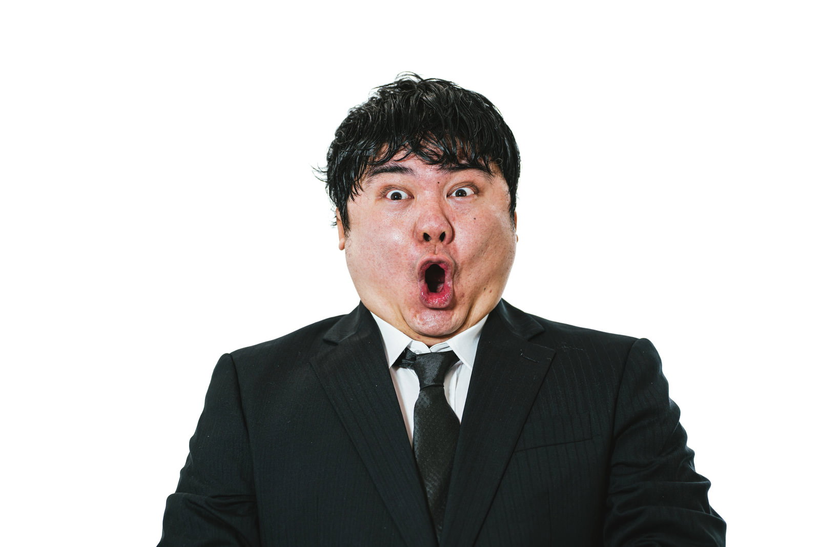 黒いスーツを着た男性が口を開けて驚いている表情［モデル：段田隼人］