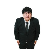 黒いスーツを着た紺色ネクタイの男性が謝罪するポーズをとるの写真