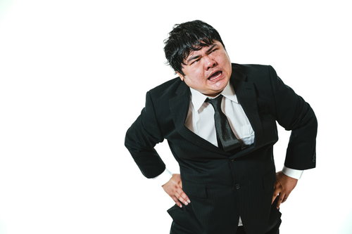 疲労コンパイルですわー、腰痛で両手を腰に当てるスーツ姿の男性