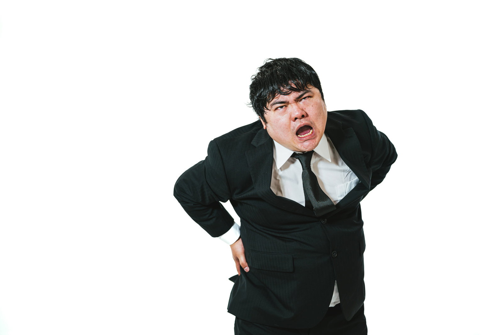 黒いスーツを着た男性が両手で頭を抱えて体調不良を訴えている［モデル：段田隼人］