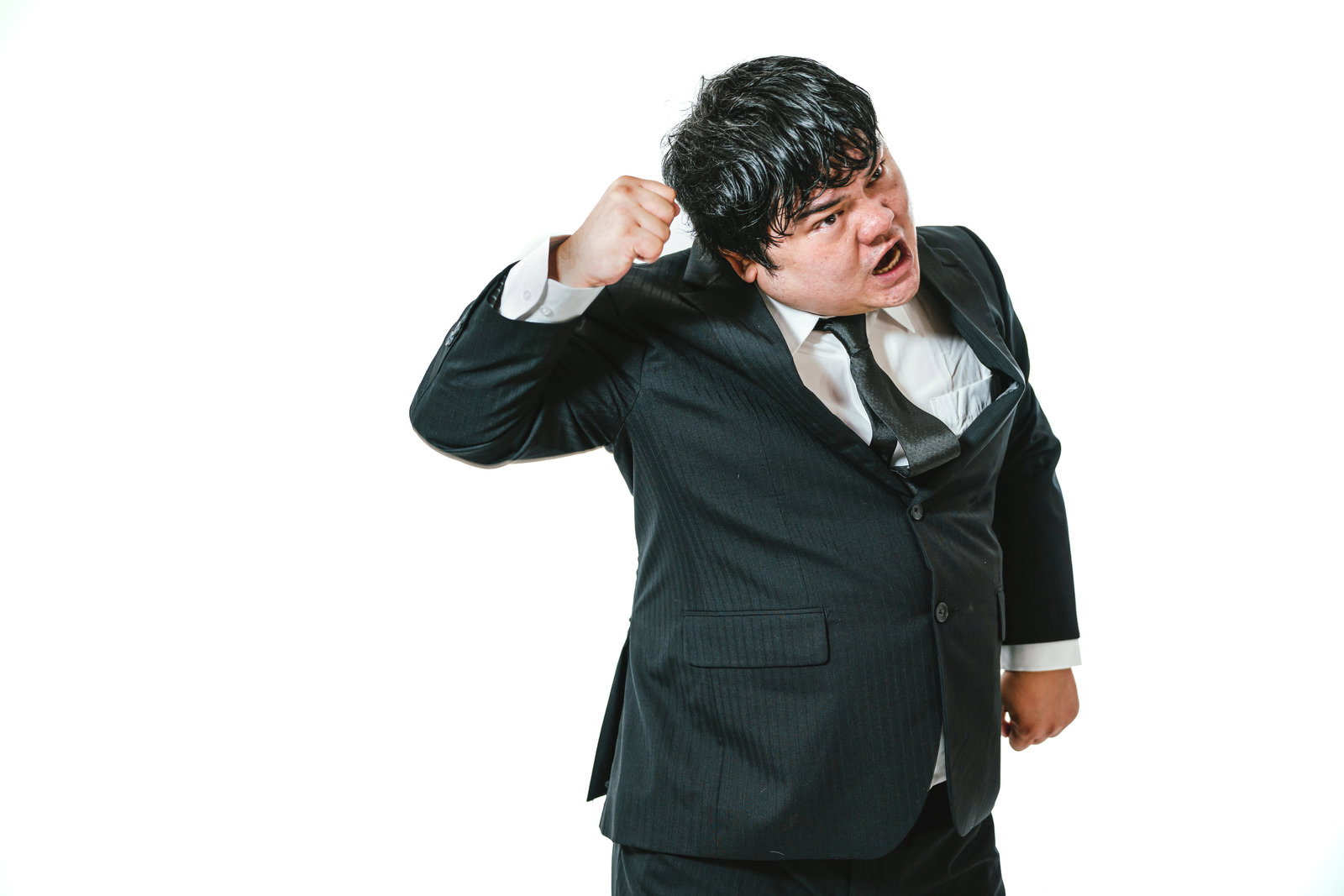 黒いスーツを着た男性が右手で拳を作って攻撃的なポーズを取っている［モデル：段田隼人］