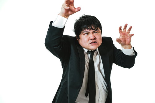 黒いスーツ姿で両手を広げて威嚇ポーズをとる会社員男性
