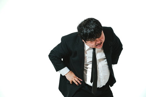 黒スーツ姿で腰を曲げて威圧的なポーズをとる男性会社員