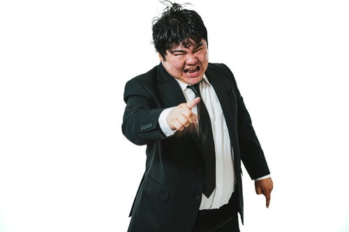 怒りに任せて怒鳴り付けるスーツ姿の男性会社員