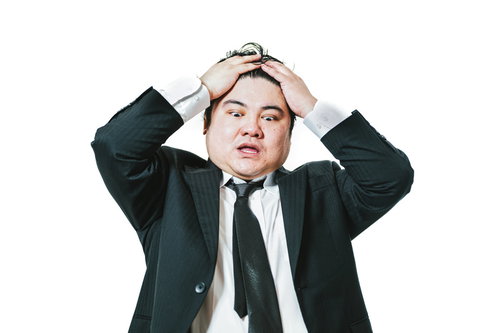 前髪を押さえて呆然とする男性会社員のビジネスポートレート