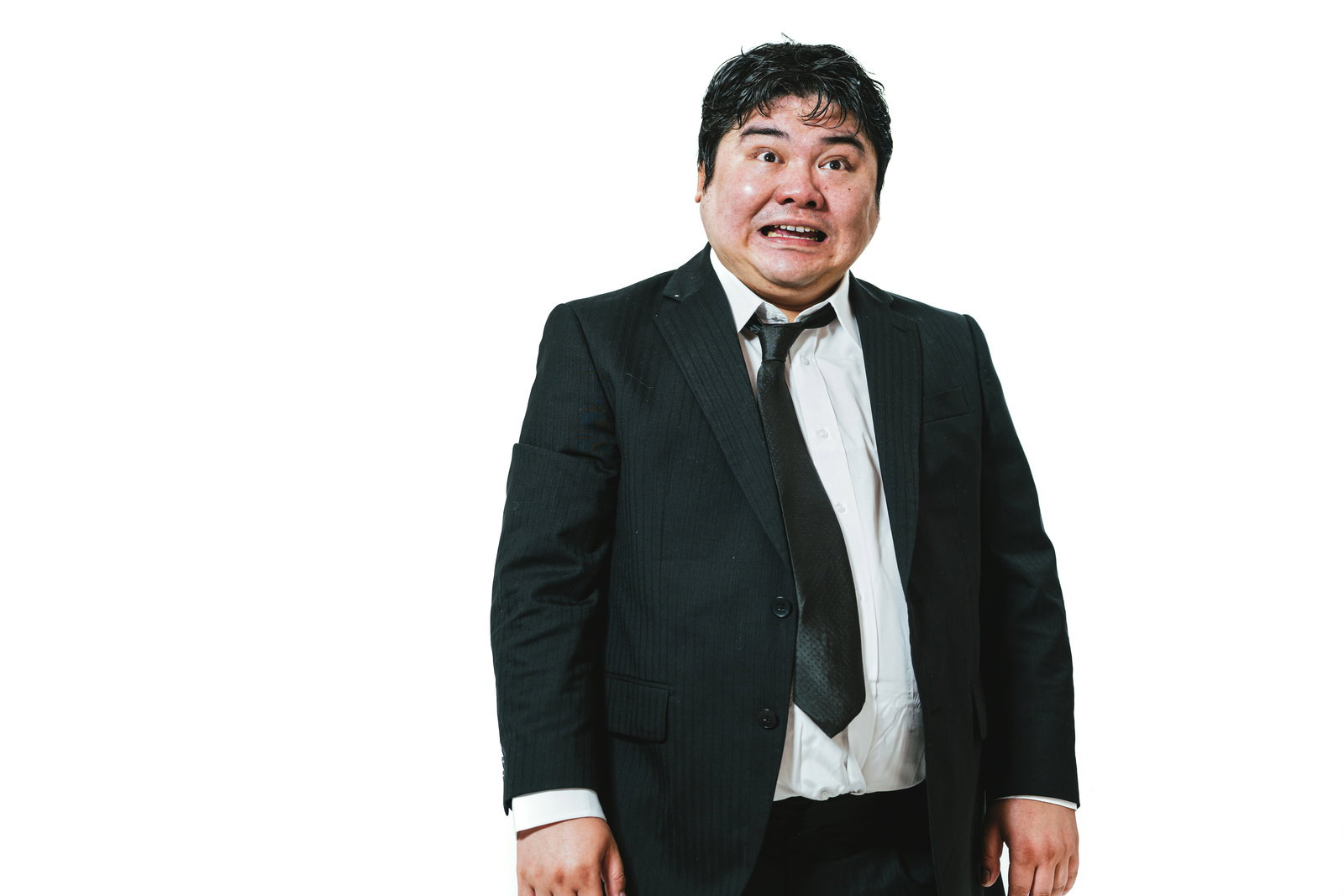 黒いスーツを着た男性が大きく口を開けて驚いている表情［モデル：段田隼人］
