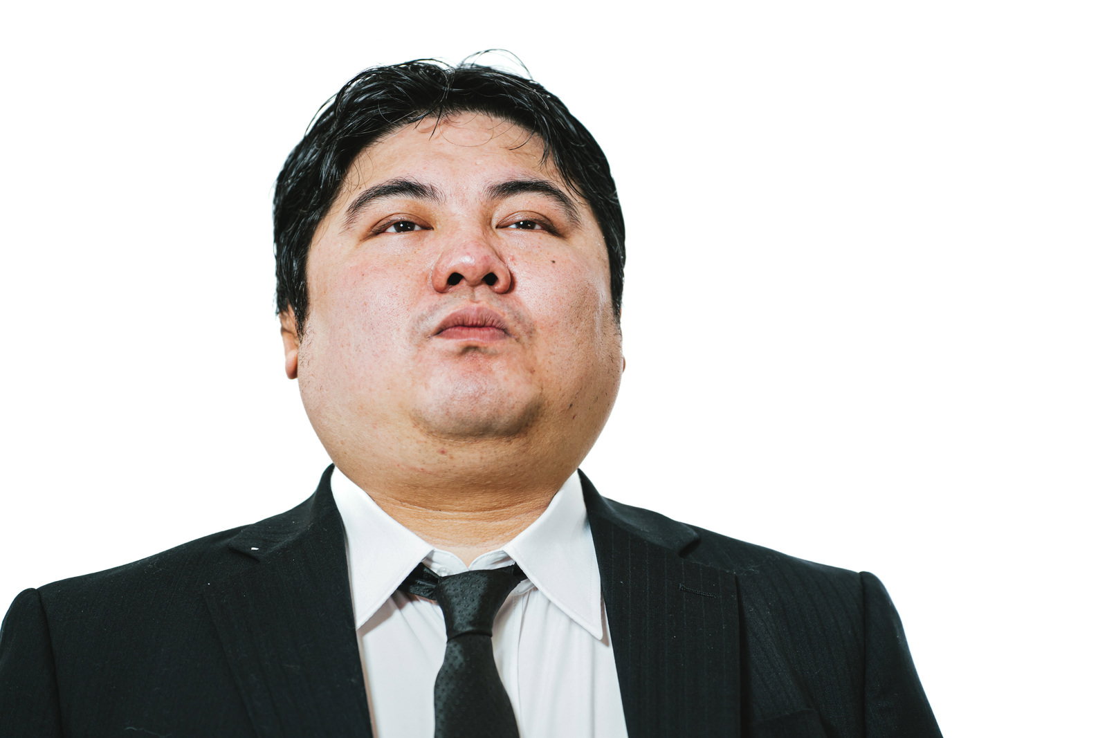 小馬鹿にした表情で正面を見るスーツ姿の男性［モデル：段田隼人］